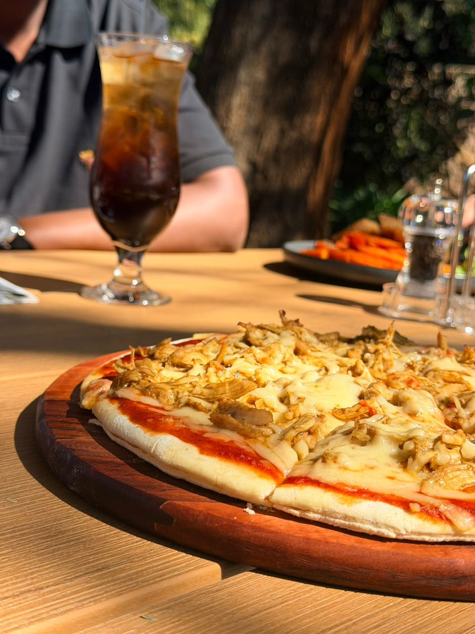 Artisan pizza served on wooden board in Kori Studio garden setting with palm trees